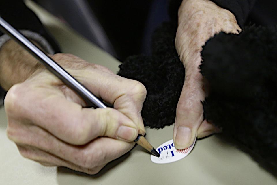 An unidentified voter writes yes on her "I Voted" sticker at a polling station in Fremont, Neb., Tuesday, Feb. 11, 2014. Fremont voters are voting on whether to scrap the city's housing restrictions that were supposed to make it hard for people living in the country illegally to live there. This new vote on the ordinance voters approved in 2010 was scheduled because city leaders are worried about possibly losing federal grants and racking up big legal bills defending the law. (AP Photo/Nati Harnik)