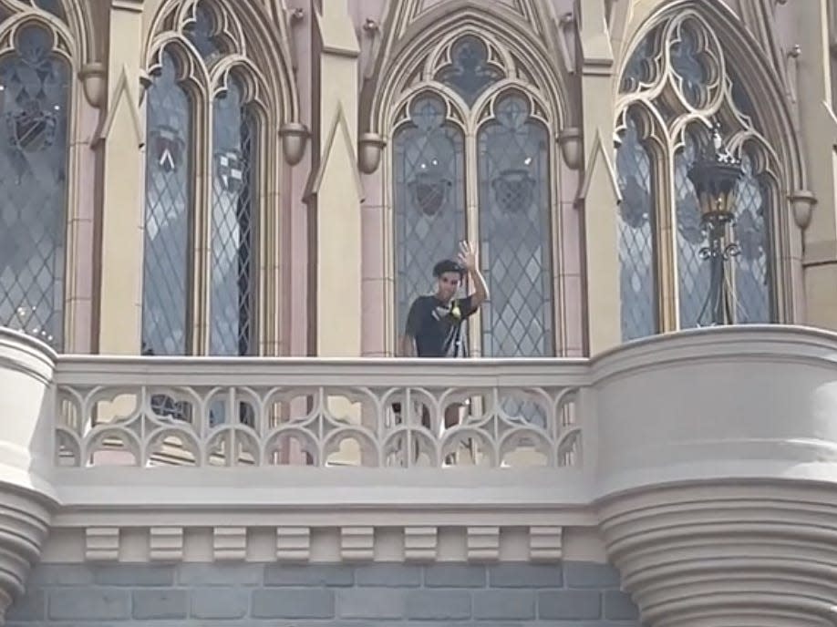 A Disney Parkgoer stands atop Cinderella Castle.