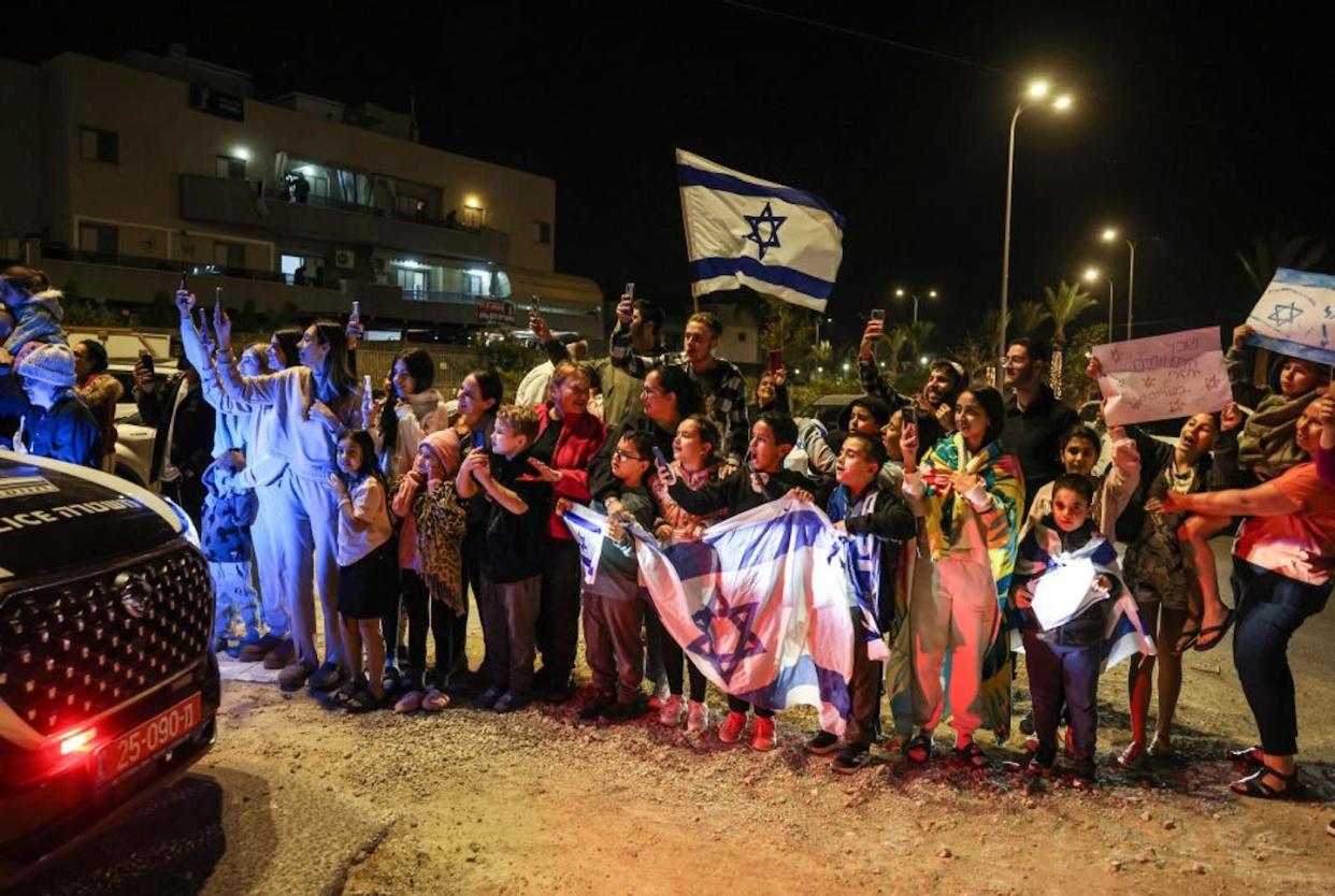 People cheer as a vehicle carrying hostages released by Hamas drives toward an army base in Ofakim, southern Israel, on Nov. 26, 2023. <a href="https://www.gettyimages.com/detail/news-photo/people-cheer-as-a-vehicle-carrying-hostages-released-by-news-photo/1803642237?adppopup=true" rel="nofollow noopener" target="_blank" data-ylk="slk:Menahem Kahana/AFP via Getty Images;elm:context_link;itc:0;sec:content-canvas" class="link ">Menahem Kahana/AFP via Getty Images </a>