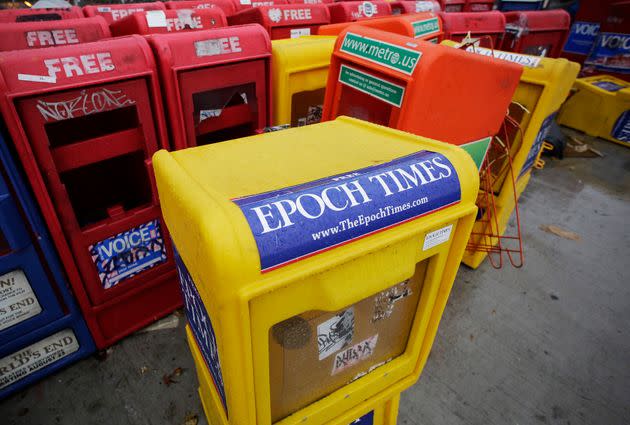 Plastic newspaper racks for The Epoch Times, The Village Voice and other papers stand along a New York City sidewalk, Nov. 27, 2013.