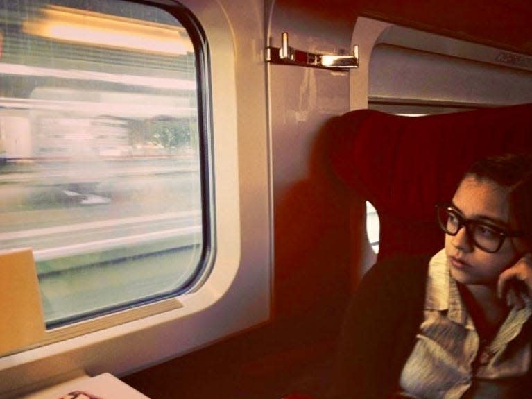 The author sits on a train to Paris looking out a window to the left