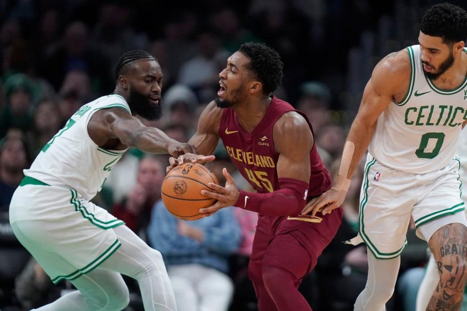 Cavaliers guard Donovan Mitchell looks for a opening past Celtics guard Jaylen Brown, left, as forward Jayson Tatum (0) defends, too, in the first half, Thursday, Dec. 14, 2023, in Boston.