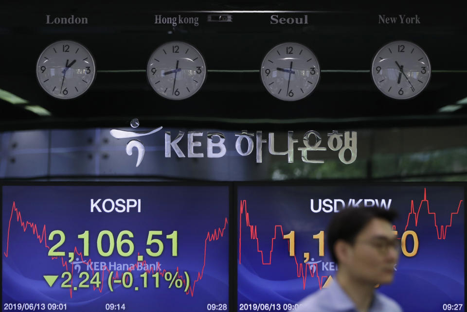A currency trader walks by the screens showing the Korea Composite Stock Price Index (KOSPI), left, and the foreign exchange rate between U.S. dollar and South Korean won at the foreign exchange dealing room in Seoul, South Korea, Thursday, June 13, 2019. Asian stocks were mixed on Thursday as protesters in Hong Kong vowed to keep opposing a proposed extradition bill they fear would whittle down the territory’s legal autonomy. (AP Photo/Lee Jin-man)