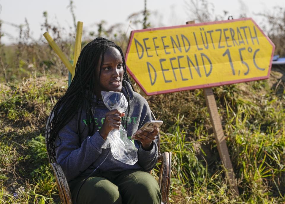 Climate activists Vanessa Nakate from Uganda reads an extract from her book at an activists camp near the Garzweiler open-cast coal mine in Luetzerath, western Germany, Saturday, Oct. 9, 2021. The village of Luetzerath, now almost entirely abandoned as the mine draws ever closer, will be the latest village to disappear as coal mining at the Garzweiler mine expands. Garzweiler, operated by utility giant RWE, has become a focus of protests by people who want Germany to stop extracting and burning coal as soon as possible. (AP Photo/Martin Meissner)