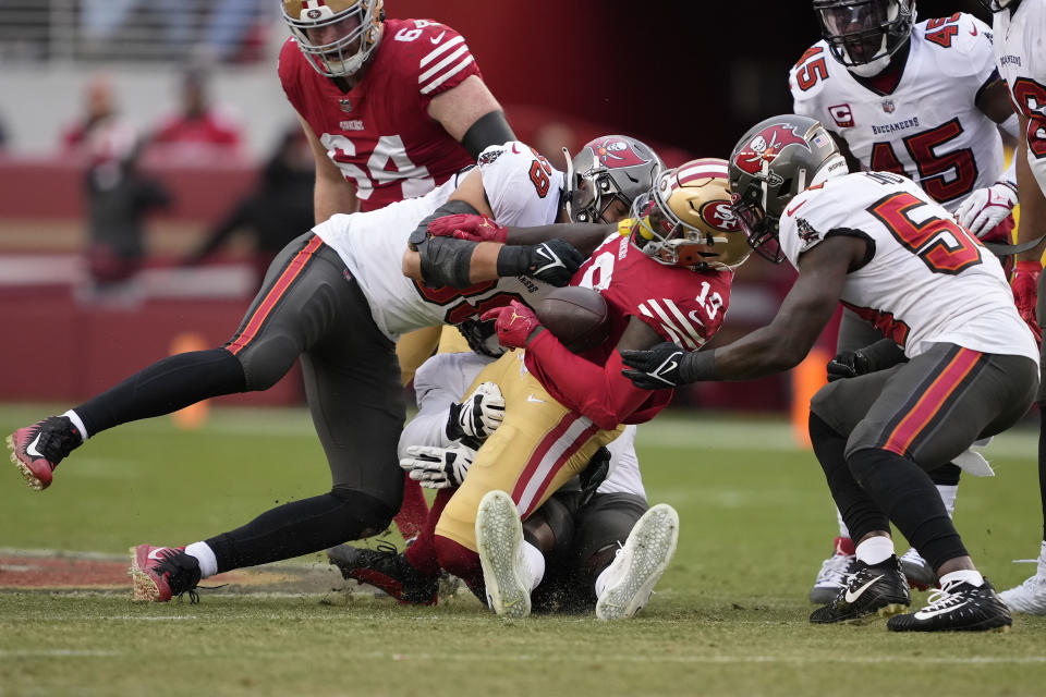 San Francisco 49ers wide receiver Deebo Samuel, middle, fumbles the ball while tackled between Tampa Bay Buccaneers linebacker Anthony Nelson, left, defensive tackle Rakeem Nunez-Roches, rear, and linebacker Lavonte David during the first half of an NFL football game in Santa Clara, Calif., Sunday, Dec. 11, 2022. The Buccaneers recovered the fumble. Samuel left the game after the play. (AP Photo/Tony Avelar)