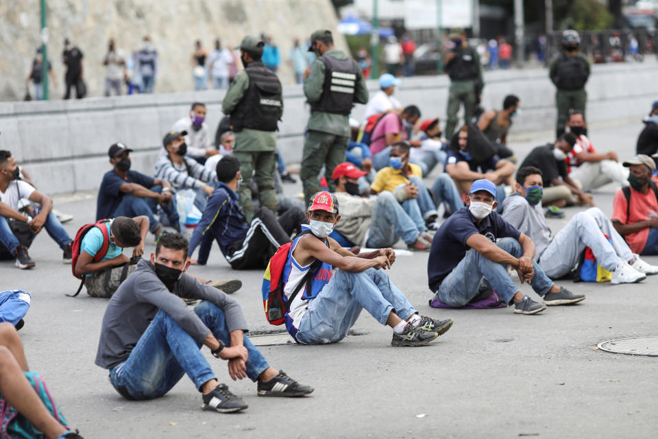 Dozens of people sit on concrete and social distance as part of punishment in Venezuela for breaking coronavirus rules. 