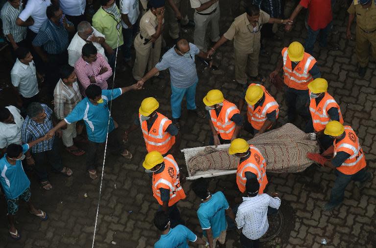 Indian personnel from the National Disaster Relief Force (NDRF) carry a body from the debris of a building collapse site in Mumbai on September 28, 2013