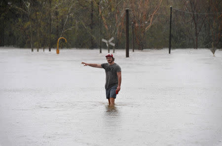 A local resident wades into flood waters blocking the road between the townships of Airlie Beach and Proserpine after Cyclone Debbie hit the area in northern Queensland, located south of Townsville. AAP/Dan Peled/via REUTERS