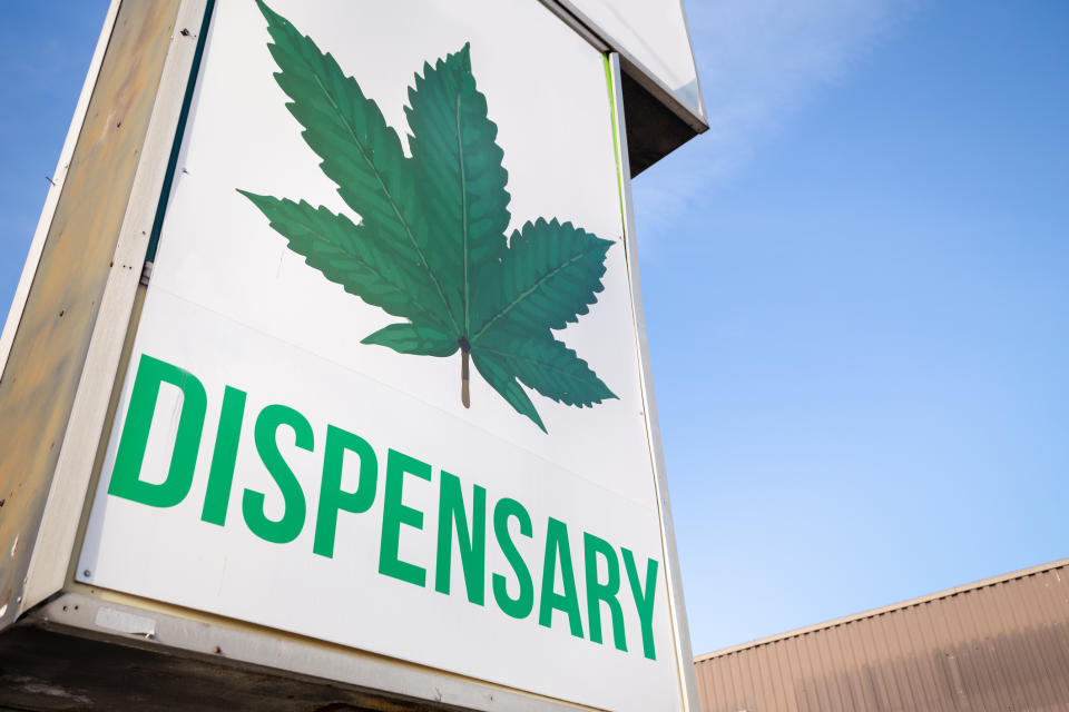 A large dispensary store sign with a cannabis leaf and the word dispensary written underneath it.