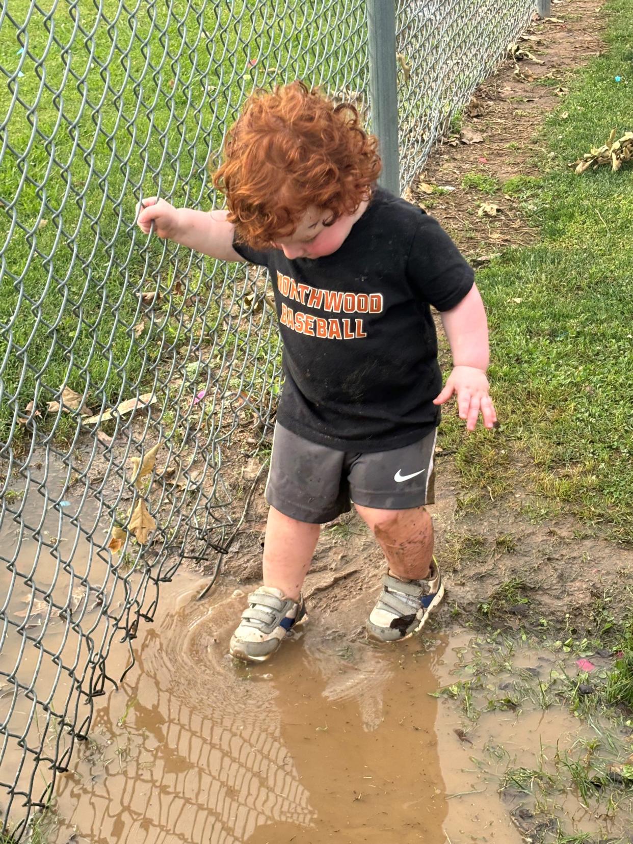 Archer Alexander, son of Northwood baseball coach Austin Alexander, dabbles in the mud during his dad's game.