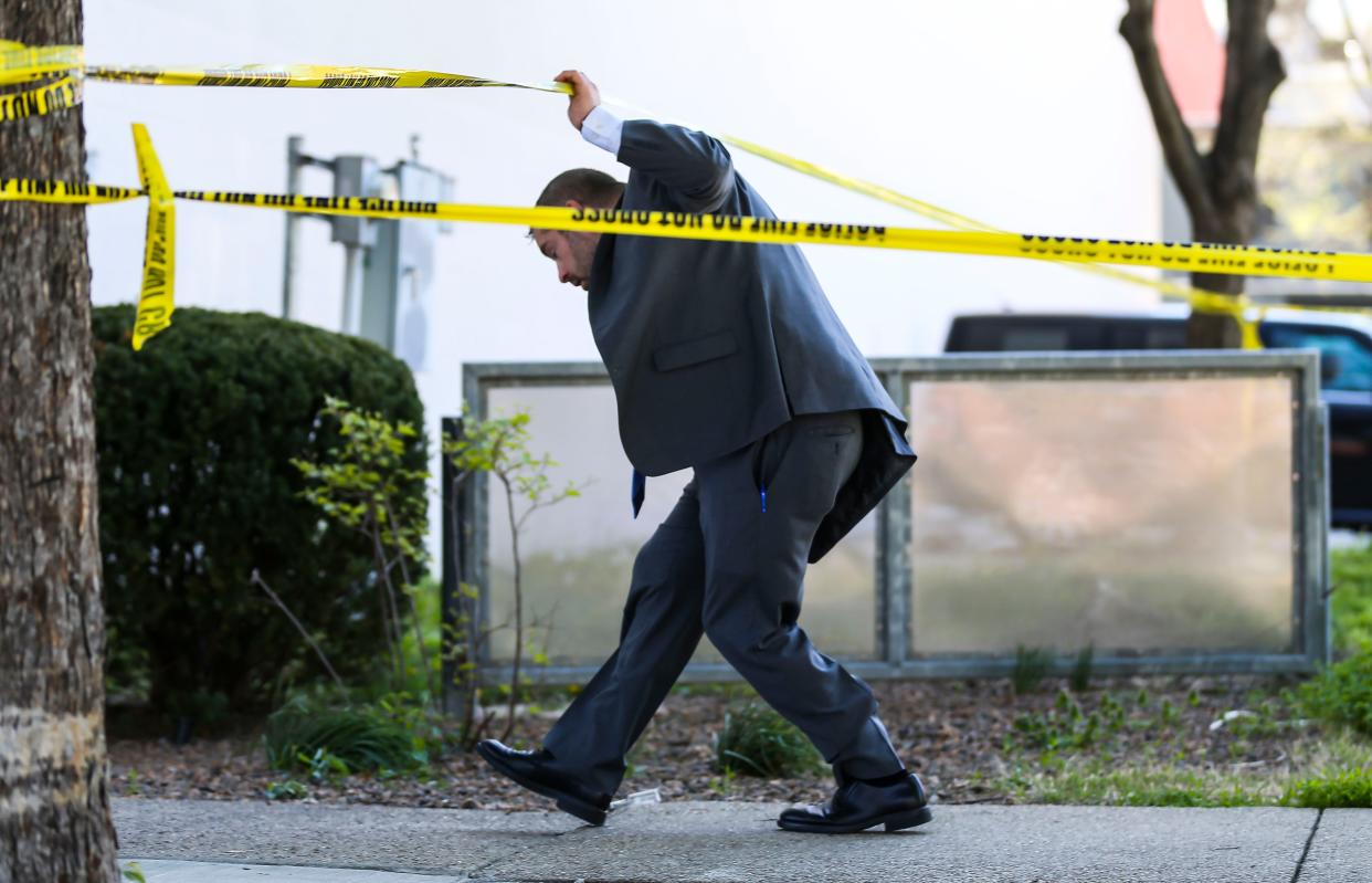 An LMPD detective walks under police tape Monday afternoon on Main Street. Five people were shot and killed, with six injured including an LMPD officer at Old National Bank Monday morning. April 9, 2023