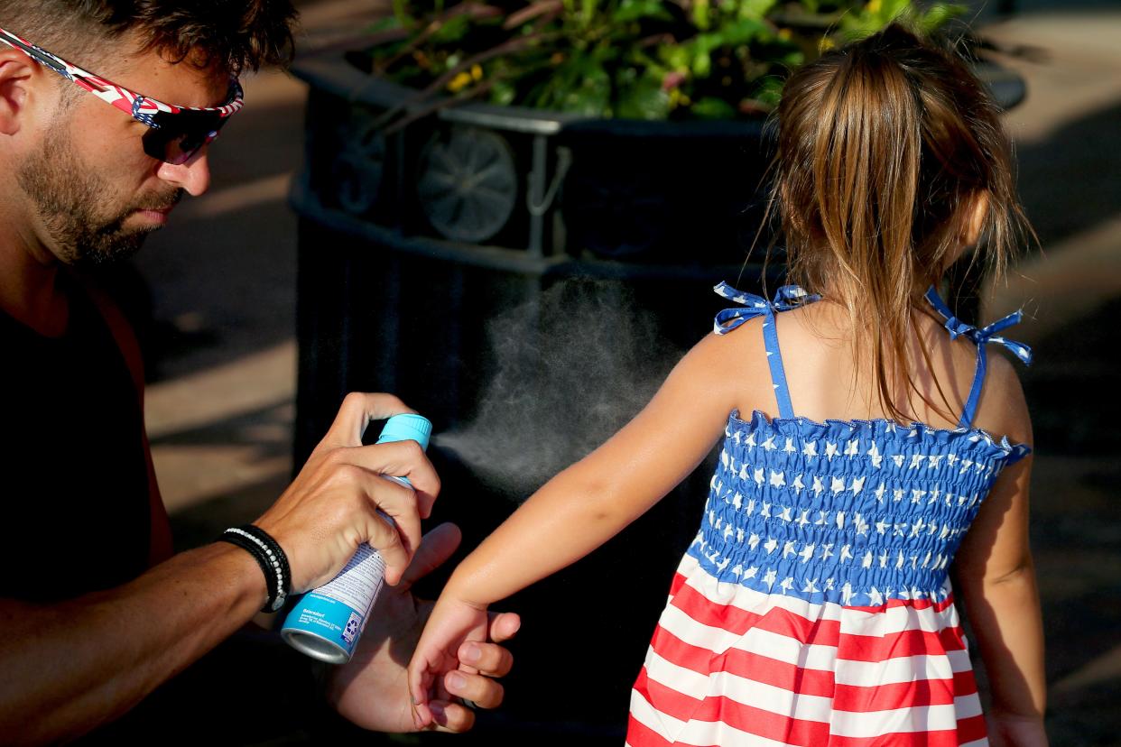 A man sprays sunscreen on his daughter in this file photo. An MU Health dermatologist provided tips to the Tribune on how to stay safe from the sun this summer.
