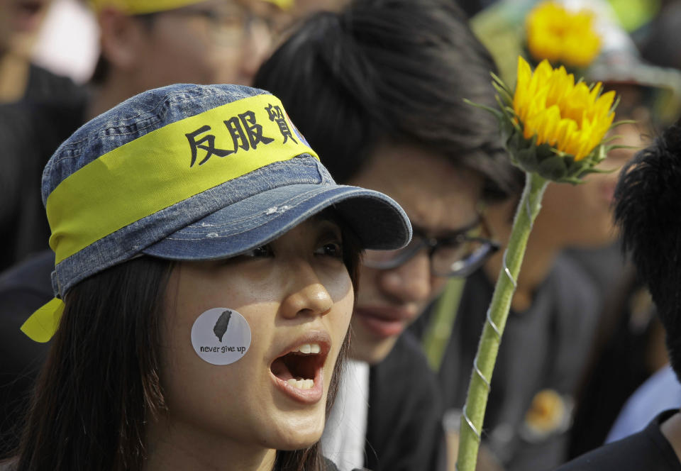 Protesters shout slogans denouncing the controversial China Taiwan trade pact during a massive protest in front of the Presidential Building in Taipei, Taiwan, Sunday, March 30, 2014. Over a hundred thousand protesters gathered in the demonstration against the island's rapidly developing ties with the communist mainland. The headband reads: "Against trade pact." (AP Photo/Wally Santana)