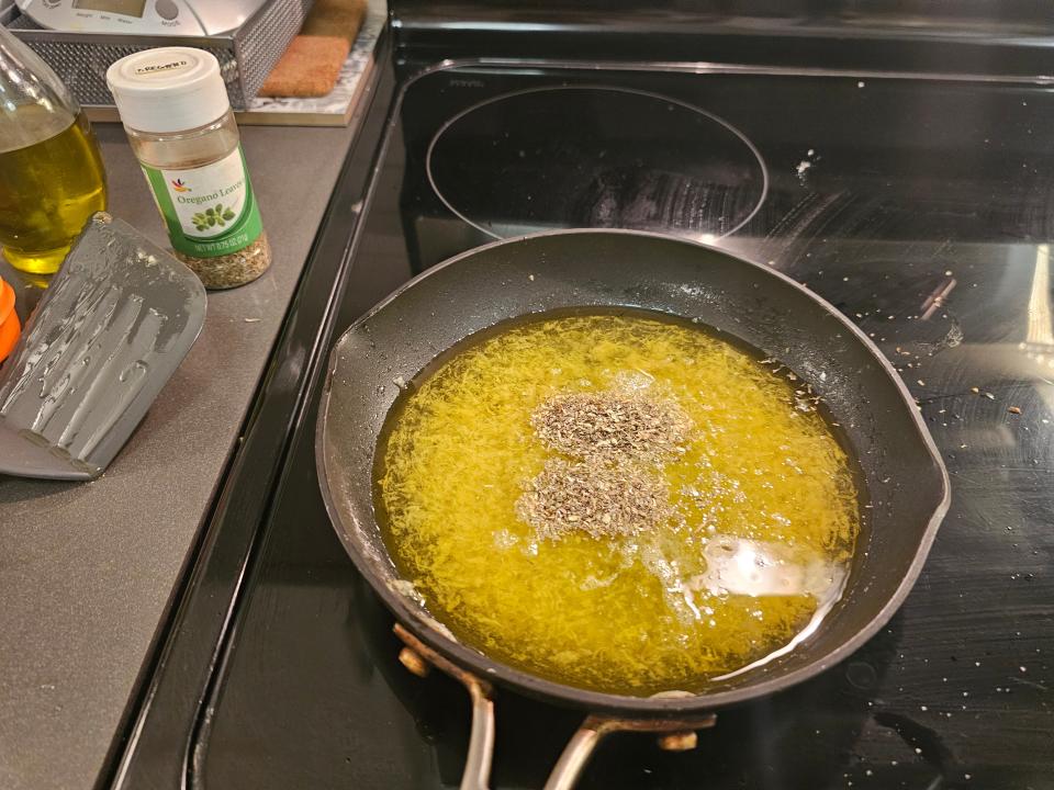 Oregano and Thyme on top of a pot of hot oil on stovetop