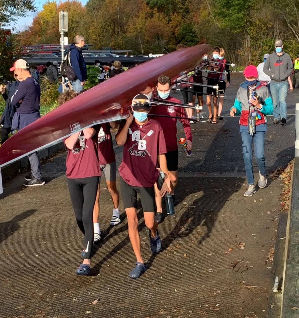 Members of the Arlington-Belmont Crew rowing team carry their shell to the water at South Watuppa Pond in Fall River as part of the Massachusetts Public School Rowing Association’s Fall Championship Regatta on Oct. 31, 2021.