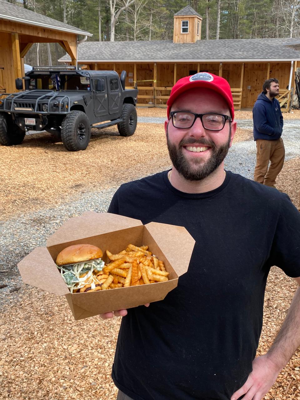 Chef Zach Wirth shows off a freshly made Nashville chicken sandwich with seasoned fries on Friday, March 10, 2023, from Deep Pond Farm's Farmhouse Kitchen food truck.