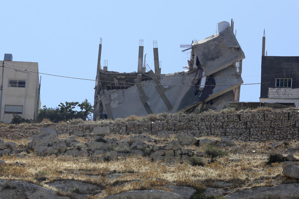 Jordanian security forces inspect the rubble Sunday, Aug. 12, 2018, after a building collapsed when assailants opened fire and set off explosions late Saturday that killed four members of the security forces trying to storm the suspected militant hideout in Salt, west of the capital of Amman. Jordanian search teams have pulled the bodies of three suspected militants from the rubble of their hideout, a government official said Sunday. (AP Photo/Raad Adayleh)