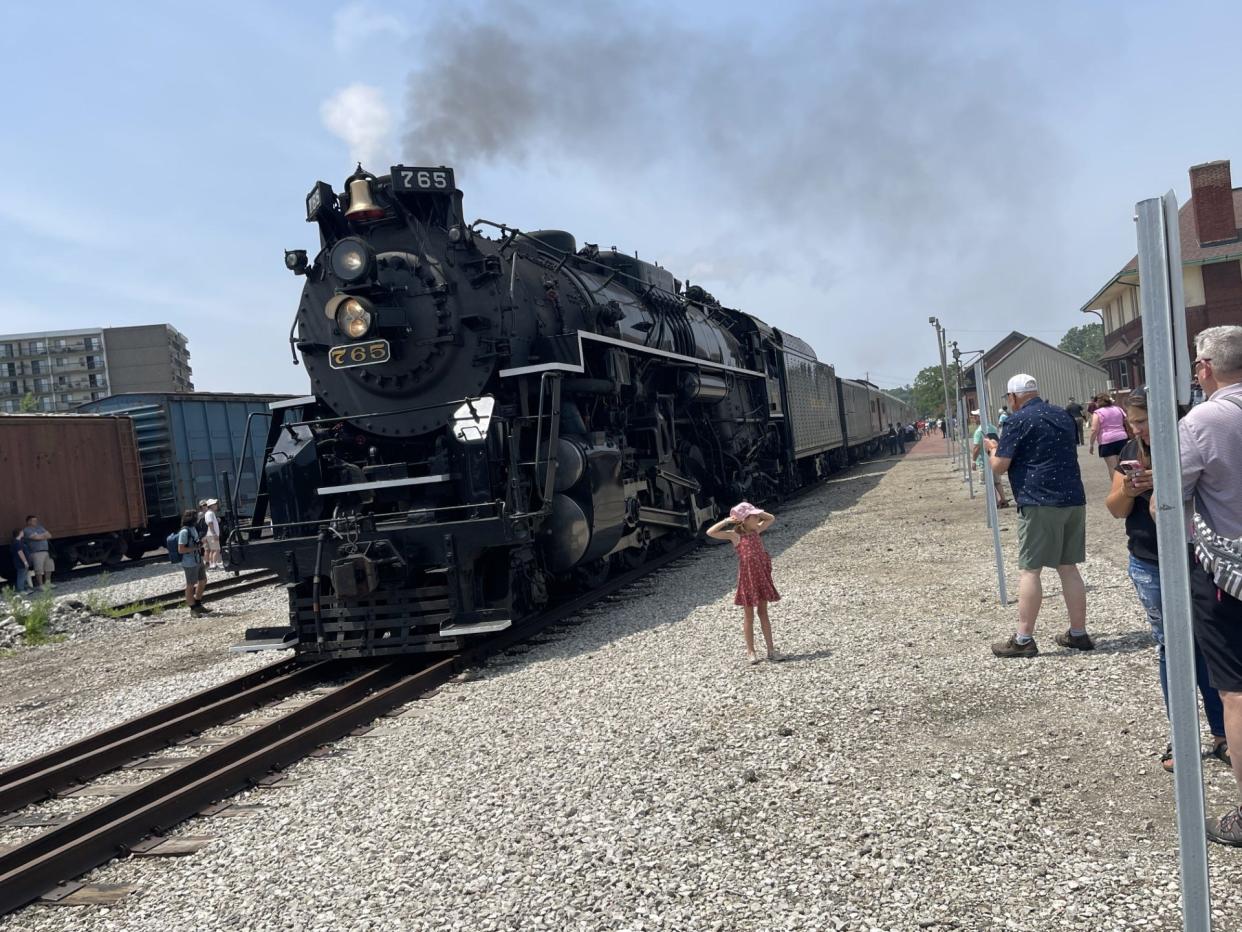 The Nickel Plate Road steam locomotive No. 765 idles at Hillsdale's historic train depot as spectators gather nearby.