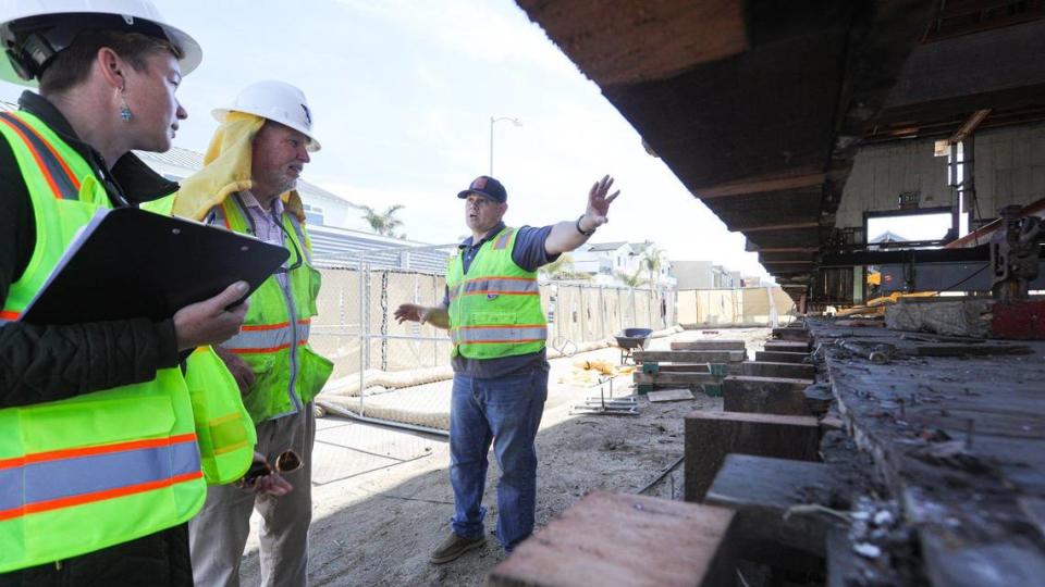 From the left, Amy Hart, California State Parks historian; Terry Paris, San Luis Obispo County project inspector, and Dave Garcia of JG Contracting talk about the Cayucos Veterans Memorial Hall, lifted 12 inches off its foundation. The vets hall is being moved so workers can replace the foundation as the historic 1870s structure is being renovated.