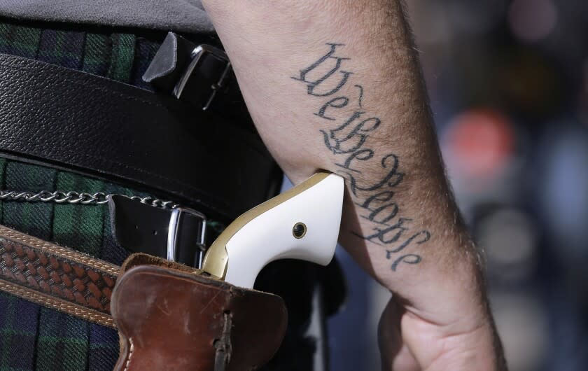FILE - In this Jan. 26, 2015 file photo, a supporter of open carry gun laws, wears a pistol as he prepares for a rally in support of open carry gun laws at the Capitol, in Austin, Texas. Texas lawmakers have given final approval to allowing people carry handguns without a license, and the background check and training that go with it. The Republican-dominated Legislature approved the measure Monday, May 24, 2021 sending it to Gov. Abbott. (AP Photo/Eric Gay, File)