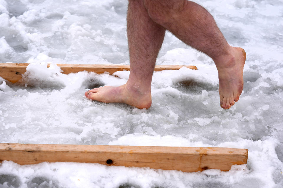 A swimmer walks barefooted through slush while heading across the ice toward the lanes during the 25 meter hat competition during the winter swimming festival on frozen Lake Memphremagog, Friday, Feb. 23, 2024, in Newport, Vermont. (AP Photo/Charles Krupa)