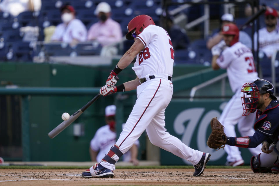 Washington Nationals' Jonathan Lucroy doubles in front of Atlanta Braves catcher Travis d'Arnaud in the second inning of an opening day baseball game at Nationals Park, Tuesday, April 6, 2021, in Washington. Hernan Perez and Andrew Stevenson scored on the play. (AP Photo/Alex Brandon)