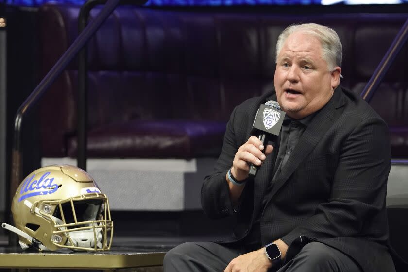 UCLA head coach Chip Kelly holds a microphone and speaks at Pac-12 media day