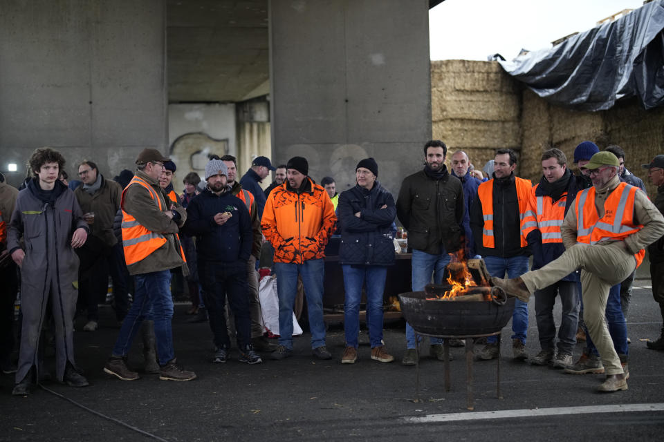 Farmers gather under a bridge as they block a highway Tuesday, Jan. 30, 2024 in Jossigny, east of Paris. With protesting farmers camped out at barricades around Paris, France's government hoped to calm their anger with more concessions Tuesday to their complaints that growing and rearing food has become too difficult and not sufficiently lucrative. (AP Photo/Christophe Ena)