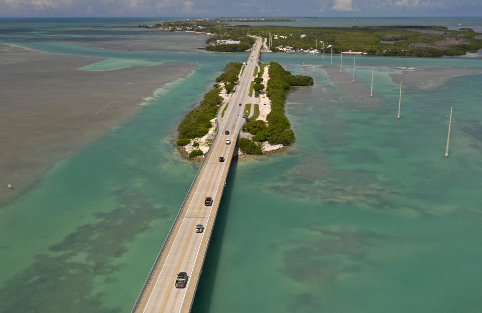 In this drone aerial photo provided by the Florida Keys News Bureau, traffic flows on the Florida Keys Overseas Highway in Islamorada, Fla., towards Key West Monday, June 1, 2020. After being closed to visitors since March 22, 2020, to help curtail the spread of COVID-19, the Florida Keys reopened to tourists Monday. Tourism employs about 45 percent of the Keys workforce. (Andy Newman/Florida Keys News Bureau via AP)