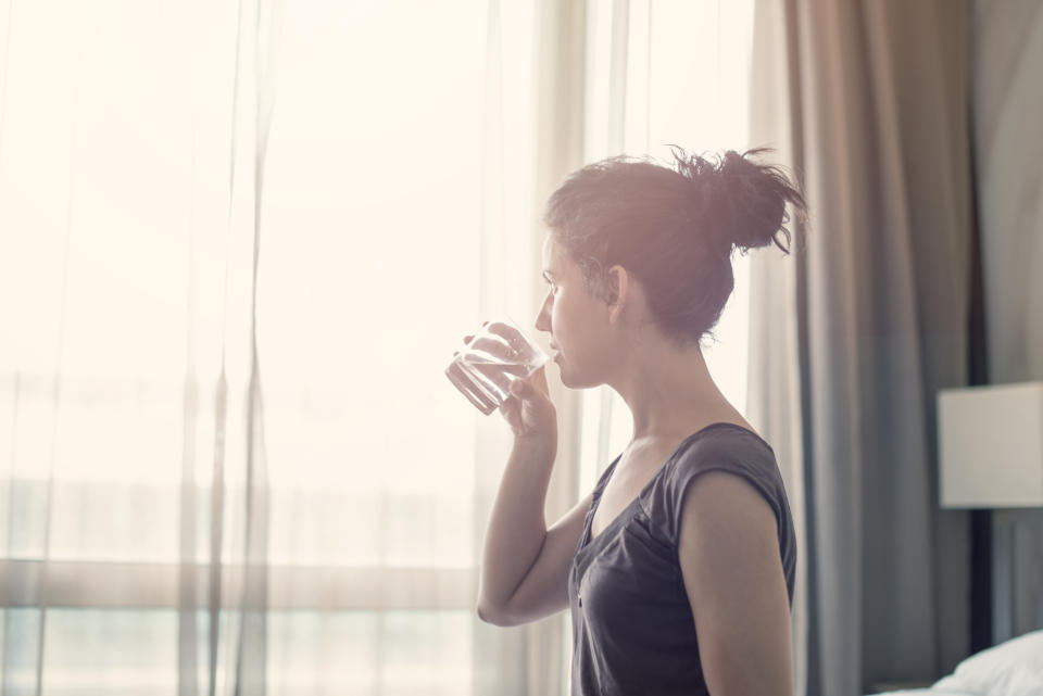 Young woman drinking water in the bedroom