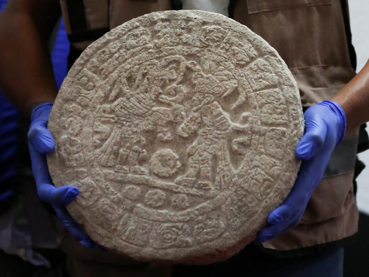 A worker shows a circular-shaped Mayan scoreboard used for a ball game found at Chichen Itza's archaeological site during a news conference, in Merida, Mexico April 11, 2023.