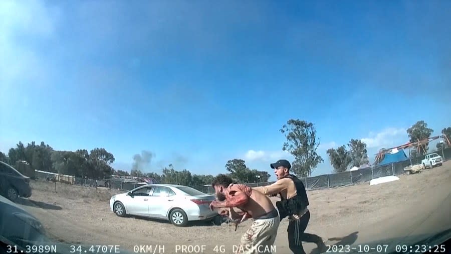 In this image from video provided by South First Responders, a man holding a weapon grabs another man next to a car during an attack by Hamas militants at the Tribe of Nova Trance music festival near Kibbutz Re’im in southern Israel on Saturday, Oct. 7, 2023. (South First Responders via AP)