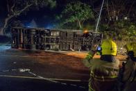 <p>This picture taken on Feb. 10, 2018 shows a firefighter (R) taking pictures at the scene after a double-decker bus toppled over in Hong Kong. (Photo: saac Lawrence/AFP/Getty Images) </p>