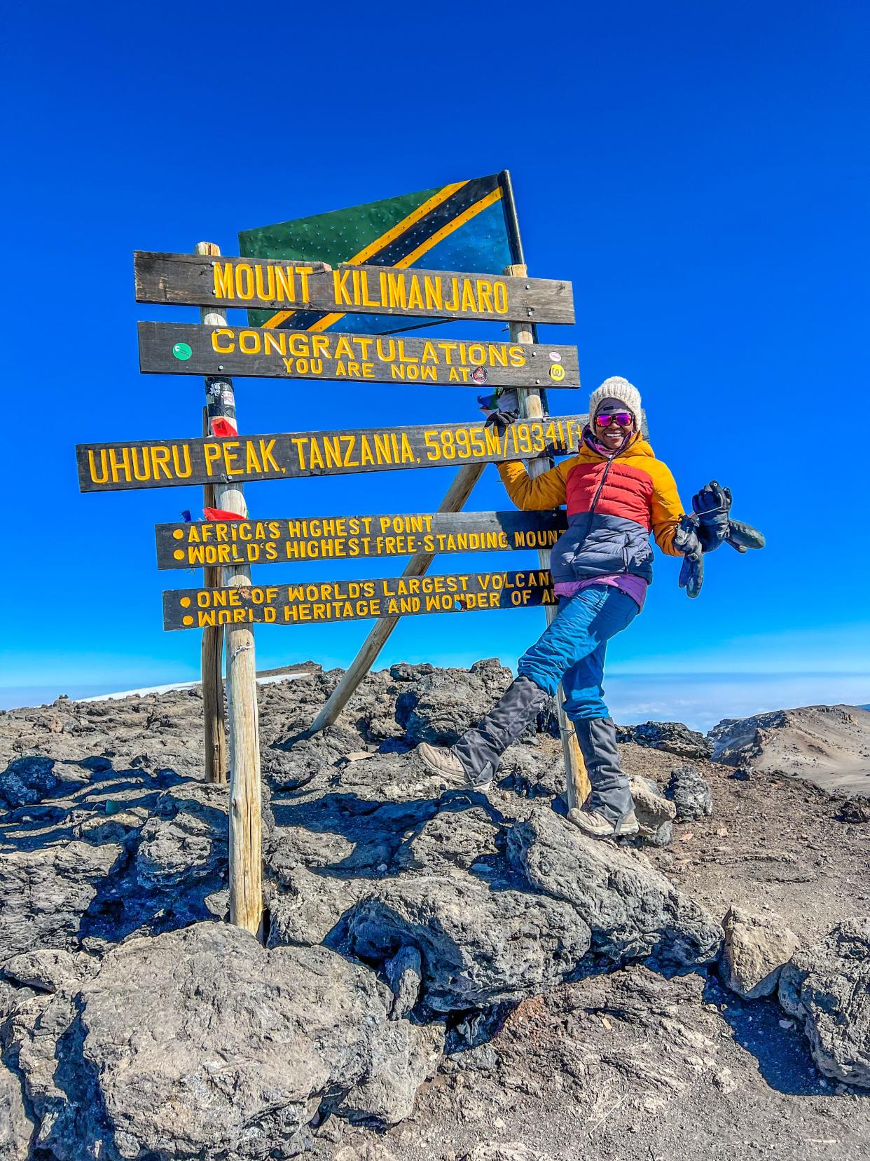 Dineo Dowd celebrates at the sign denoting the summit of Tanzania's Kilimanjaro.