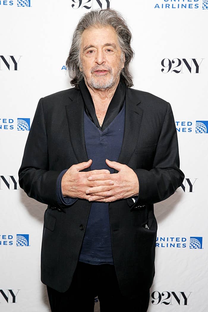 Al Pacino with his hands clasped together as he stands on the red carpet