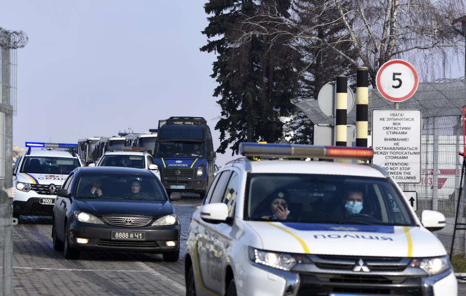 A motorcade with police cars and busses with passengers from the Ukrainian aircraft chartered by the Ukrainian government for evacuation from the Chinese city of Wuhan, leave the the gate upon their landing at airport outside Kharkiv, Ukraine, Thursday, Feb. 20, 2020. Ukraine's effort to evacuate more than 70 people from China due to the outbreak of the new COVID-19 virus was delayed because of bad weather as evacuees travel to a hospital where they are expected to be quarantined. (AP Photo/Igor Chekachkov)