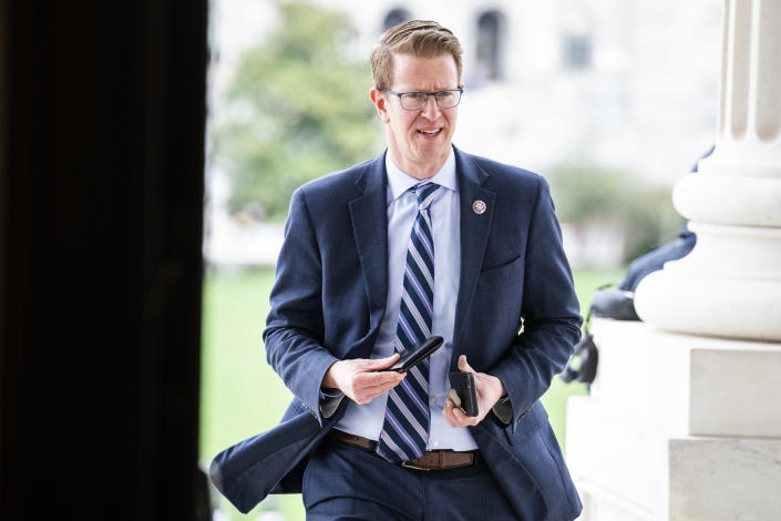 Rep. Derek Kilmer rushes past a column, holding his cellphone.