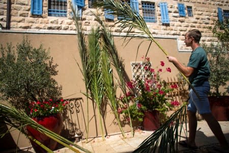 15 year old Adin Stanleigh cleans palm branches used to cover their sukka, or ritual booth, used during the Jewish holiday of Sukkot in his yard, in Jerusalem