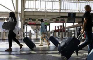 Travelers walk with their suitcase on the day of a national strike of France's national state-owned railway company SNCF to raise wages at Gare de Lyon train station in Paris on July 6, 2022. - Three high-speed trains (TGV) out of four running on some lines, and two Regional trains (TER) out of five : the strike of the employees of the SNCF disrupted on July 6, 2022 morning the departure for summer vacations for many travelers. (Photo by Geoffroy Van der Hasselt / AFP)