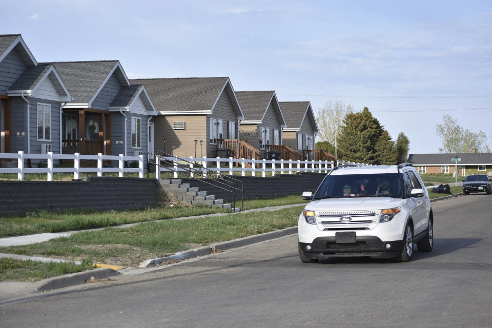 In this Wednesday, May 19, 2021, photo, an SUV drives down a residential street on the Fort Berthold Indian Reservation in Parshall, North Dakota. Oil pumped from Native American lands in the U.S. increased about tenfold since 2009 to more than 130 million barrels annually, bringing new wealth to about a dozen tribes. (AP Photo/Matthew Brown)