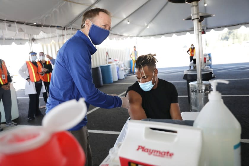 LAUSD Superintendent Austin Beutner, left, pretends to vaccinate Los Angeles Rams linebacker Kenny Young.