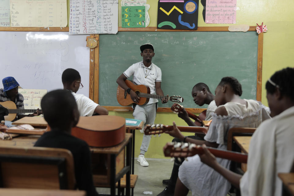 Students take a guitar lesson with Hebert Michel at Plezi Mizik Composition Futures School in Port-au-Prince, Haiti, Thursday, Sept. 21, 2023. The program's teachers and students decide together what music they’ll play, spanning genres that include compas, reggae, rock, Latino music and African music. (AP Photo/Odelyn Joseph)