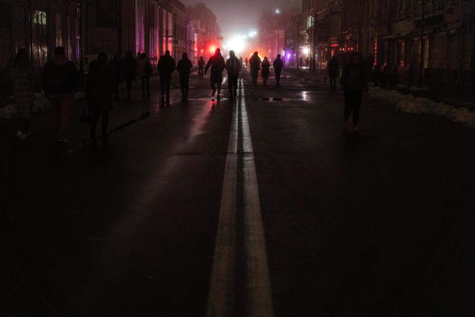 People walk through the city center which lost electrical power after a Russian rocket attack in Kyiv, Ukraine, Nov. 24, 2022.