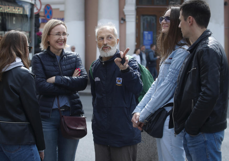 In this Saturday, May 25, 2019 photo Vyacheslav Rasner, 68, leads clients around some parts of the city's Nevsky Prospekt main avenue in St.Petersburg, Russia, as he has become an unexpectedly popular tour guide after surviving a decade of homelessness. Rasner guides tourists around the ornate magnificence and the cruel poverty of the city, a good education for visitors who have already seen the city’s more-renowned sights, but his erudition and affection for the city shine through. (AP Photo/Dmitri Lovetsky)