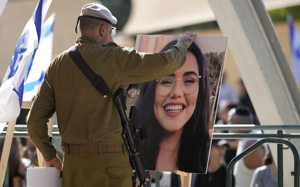 A soldiers adjust a photo of Noa Marciano, a soldier in the Israel Defense Forces, which is displayed at her funeral