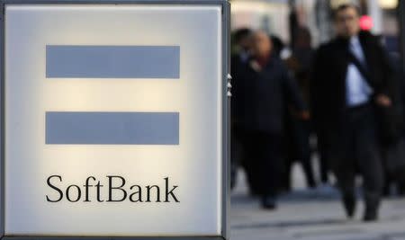 People walk behind the logo of SoftBank Corp in Tokyo December 18, 2014. REUTERS/Toru Hanai