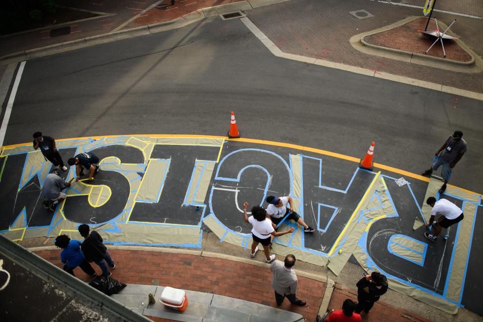 Artists work on taping off the letters for “End Racism Now” and “Black Lives Do Matter” slogans around the Market House on Monday, June 29, 2020. The City of Fayetteville will partnered with Cool Spring Downtown District, The Arts Council of Fayetteville/Cumberland County, and Fayetteville State University for the project. 