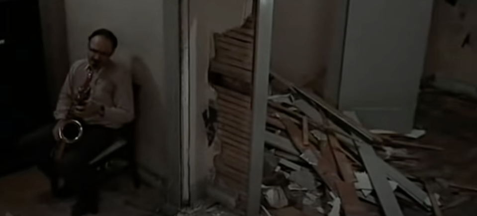 A man plays a saxophone in a dilapidated house