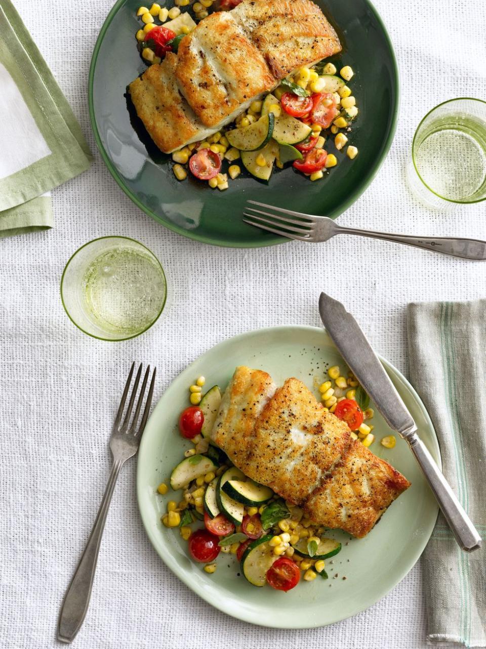 seared grouper with corn, zucchini, and tomato on a green plate