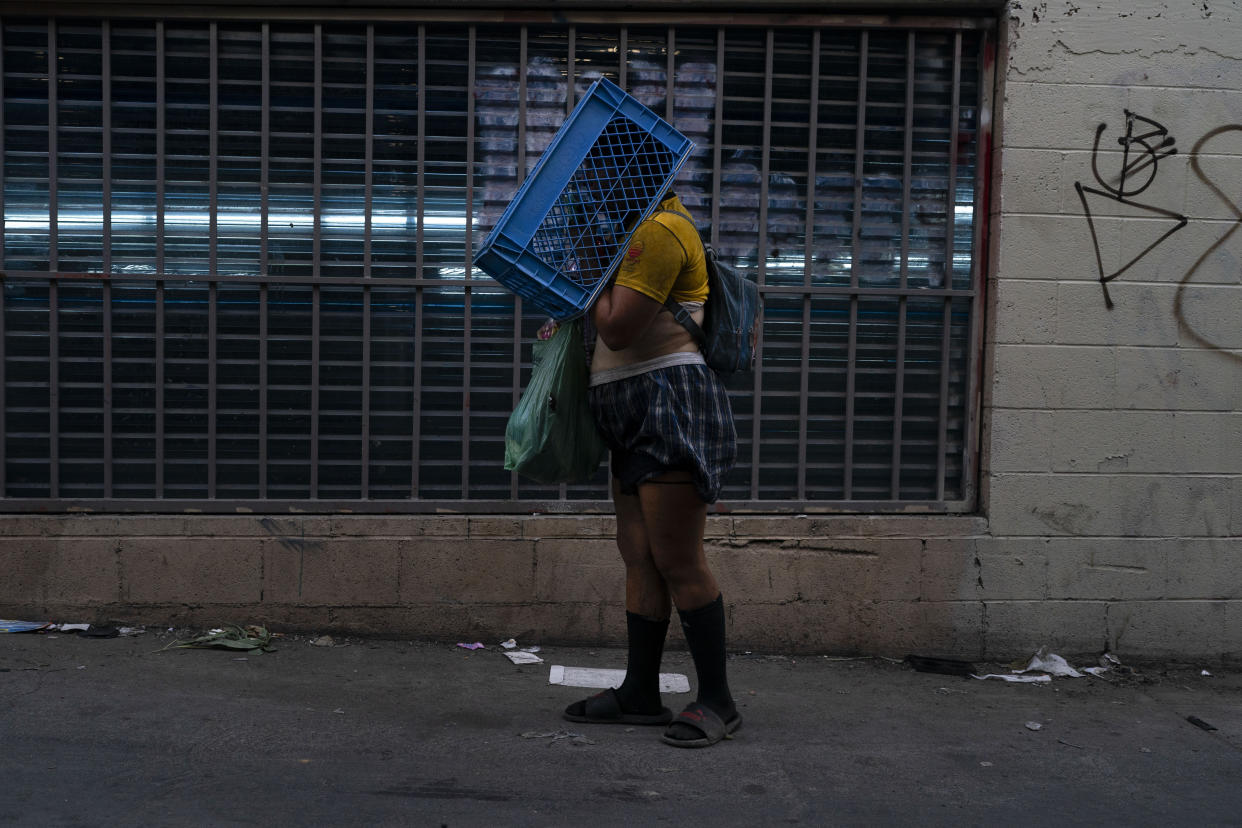A mentally ill homeless woman mumbles to herself while standing in an alley with a crate over her head in Los Angeles, Tuesday, Aug. 9, 2022. (AP Photo/Jae C. Hong)